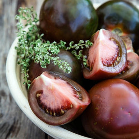 Black Krim indeterminate tomato seeds from SeedsNow, with close-up of dark red and green heirloom tomato seedlings.